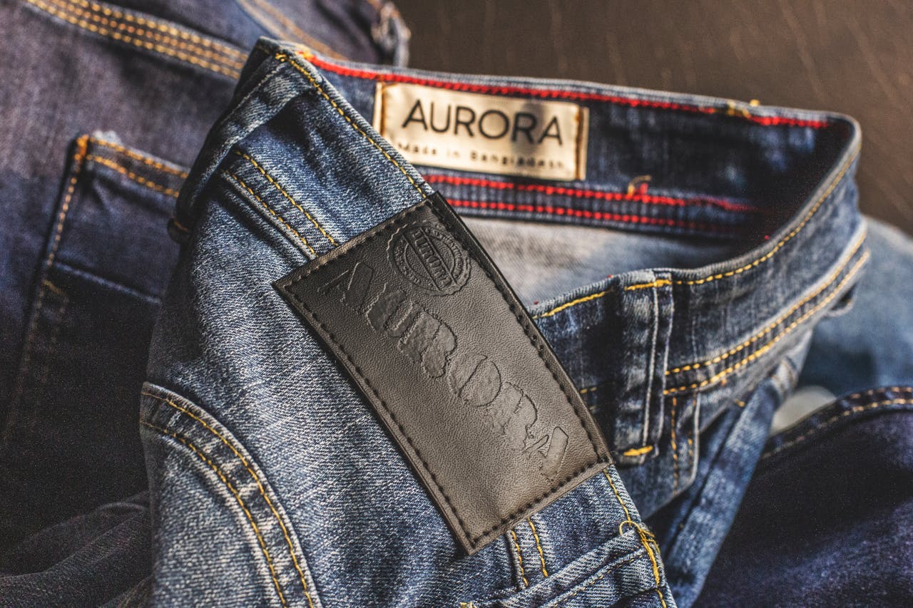 Close-up of blue denim jeans showcasing Aurora label, made in Bangladesh.
