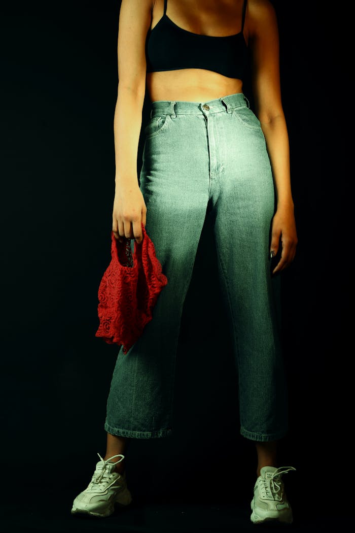 Stylish woman modeling trendy denim and sneakers in moody lighting.
